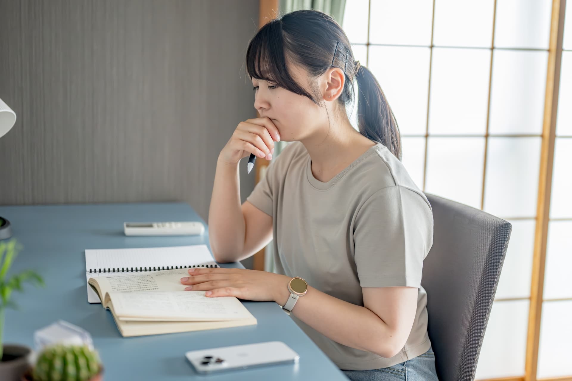 水色の机で勉強をする女性